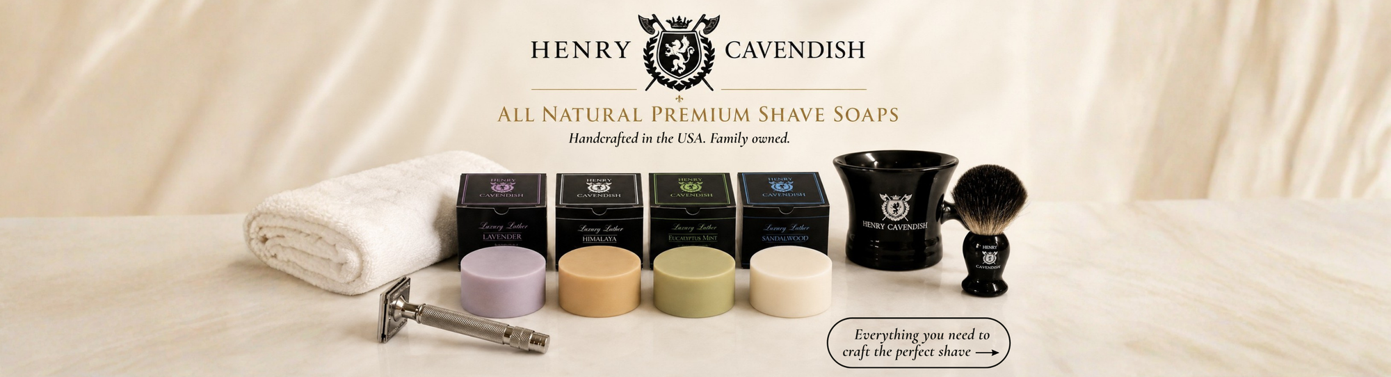 Henry Cavendish All Natural Premium Shave Soaps set displayed on a cream fabric surface, featuring multiple colored soap bars, a white towel, a metal razor, and grooming tools against a neutral background.
