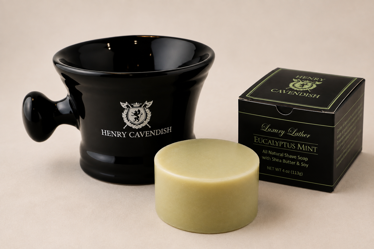 Henry Cavendish Luxury Lather Eucalyptus Mint natural shaving soap, showing the pale yellow-green solid puck a black ceramic lather mug with the brand logo, and the black retail box on a neutral beige background.